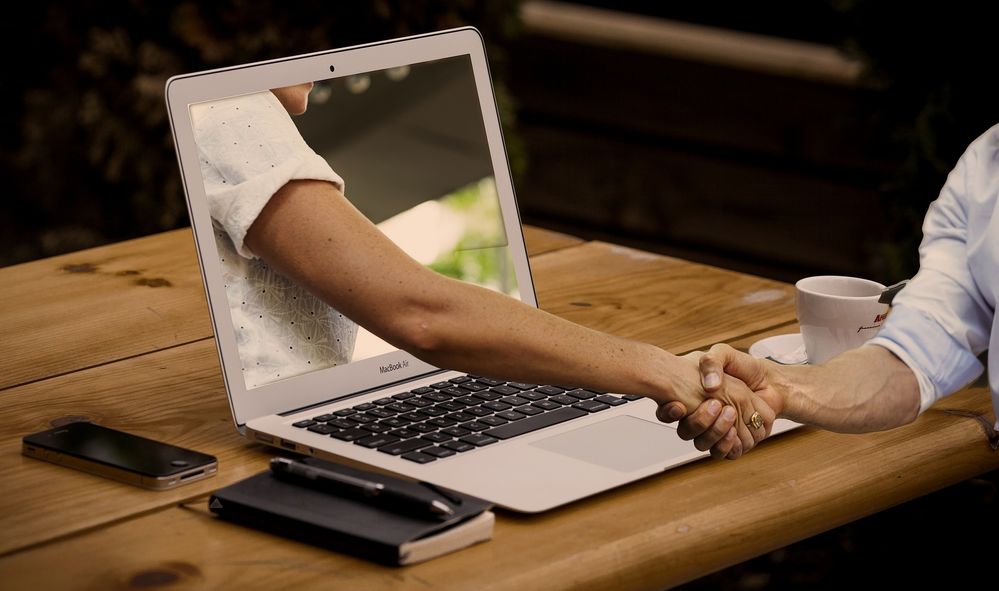 a Handshake with one arm reaching out through a computer screen